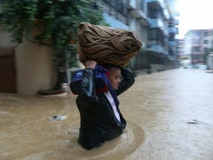Ein Nepalese kämpft sich durch eine überflutete Strasse in der Hauptstadt Kathmandu. (Bild: KEYSTONE/AP/NIRANJAN SHRESTHA)