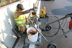 Ein Mitarbeiter zieht den Schacht am Strassenrand so ein, dass am Ende alles wieder perfekt ebenerdig sein wird.