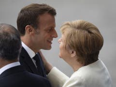 Der französische Präsident Emanuel Macron begrüsst die deutsche Bundeskanzlerin Angela Merkel vor der Parade. (Bild: Keystone/EPA/IAN LANGSDON)