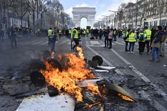 Protestierende Gilets jaunes vor brennenden Barrikaden auf den Champs-Élysées. (Bild: Getty Images)