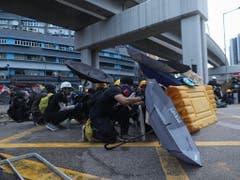 Demonstrierende in Hongkong schützen sich mit Regenschirmen. (Bild: KEYSTONE/EPA/JEROME FAVRE)