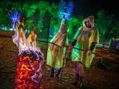 Das 44. Paléo Festival in Nyon ging am Sonntag zu Ende: Auch der Regen konnten dem Openair nichts anhaben. Besucher in Regenpellerinen stehen an einer Feuerstelle. (Bild: KEYSTONE/VALENTIN FLAURAUD)