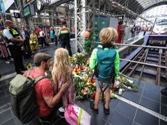 Passanten legen am Gleis im Frankfurter Hauptbahnhof, an dem der achtjährige Bub starb, Blumen nieder. (Bild: KEYSTONE/EPA/ARMANDO BABANI)