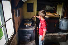 Samuel wendet die Rösti, die in zwei Pfannen auf dem Holzkochherd gebraten wird.