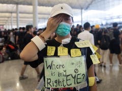 Aktivisten skandierten im Flughafen Parolen: Die Polizei solle einem Demonstranten, der durch ein Gummigeschoss schwer im Gesicht verletzt worden war, sein Auge «zurückgeben». (Bild: KEYSTONE/EPA/JEROME FAVRE)