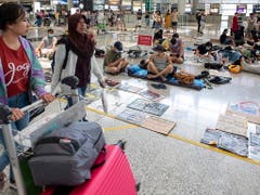 Passagiere gehen am Flughafen von Hongkong an Protestierenden vorbei. (Bild: KEYSTONE/EPA/MIGUEL CANDELA)