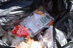 Die Ausbeute von 22 Minuten Müll sammeln: ein Plastiksack voller Müll. Besonders sinnlos erscheinen gewisse Fundstücke: Jemand achtete beim Kauf dieser Wiener Würstchen darauf, dass sie Bio sind und auch andere Labels auf der Verpackung drücken die Nachhaltigkeit für den Planeten aus. Wenn aber dieses Produkt in Plastik verpackt wird und diese Verpackung wiederum im Wald landet, steht es schlecht um die Ökobilanz des Produktes. (Bild: Jessica Nigg)