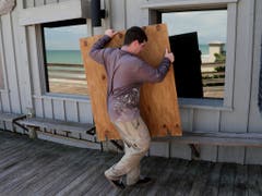 In Vero Beach in Florida macht ein Mann sein Grilllokal möglichst sturmfest. (Bild: KEYSTONE/AP/LYNNE SLADKY)