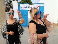 Zwei Frauen vor einem Wahllokal in Tunis mit tintengefärbtem Zeigefinger - der Beleg, dass sie an den Präsidentenwahlen teilnahmen. (Bild: KEYSTONE/EPA/MOHAMED MESSARA)