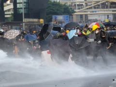 Demonstranten schützen sich mit Schirmen vor den Wasserkanonen. (Bild: KEYSTONE/EPA/VIVEK PRAKASH)
