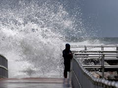 Ein Fischer in Florida trotzt den Riesenwellen. (Bild: KEYSTONE/AP Orlando Sentinel/JOE BURBANK)