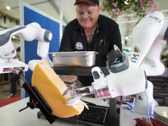 Ein Roboter streicht eine Portion Raclette auf einen Teller. Das Gerät wurde am Samstag an einer Messe in Martigny VS vorgestellt. (Bild: KEYSTONE/LAURENT GILLIERON)