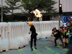 Ein Regierungsgegner wirft bei Protesten in Hongkong einen Molotow-Cocktail. (Bild: KEYSTONE/AP/VINCENT THIAN)